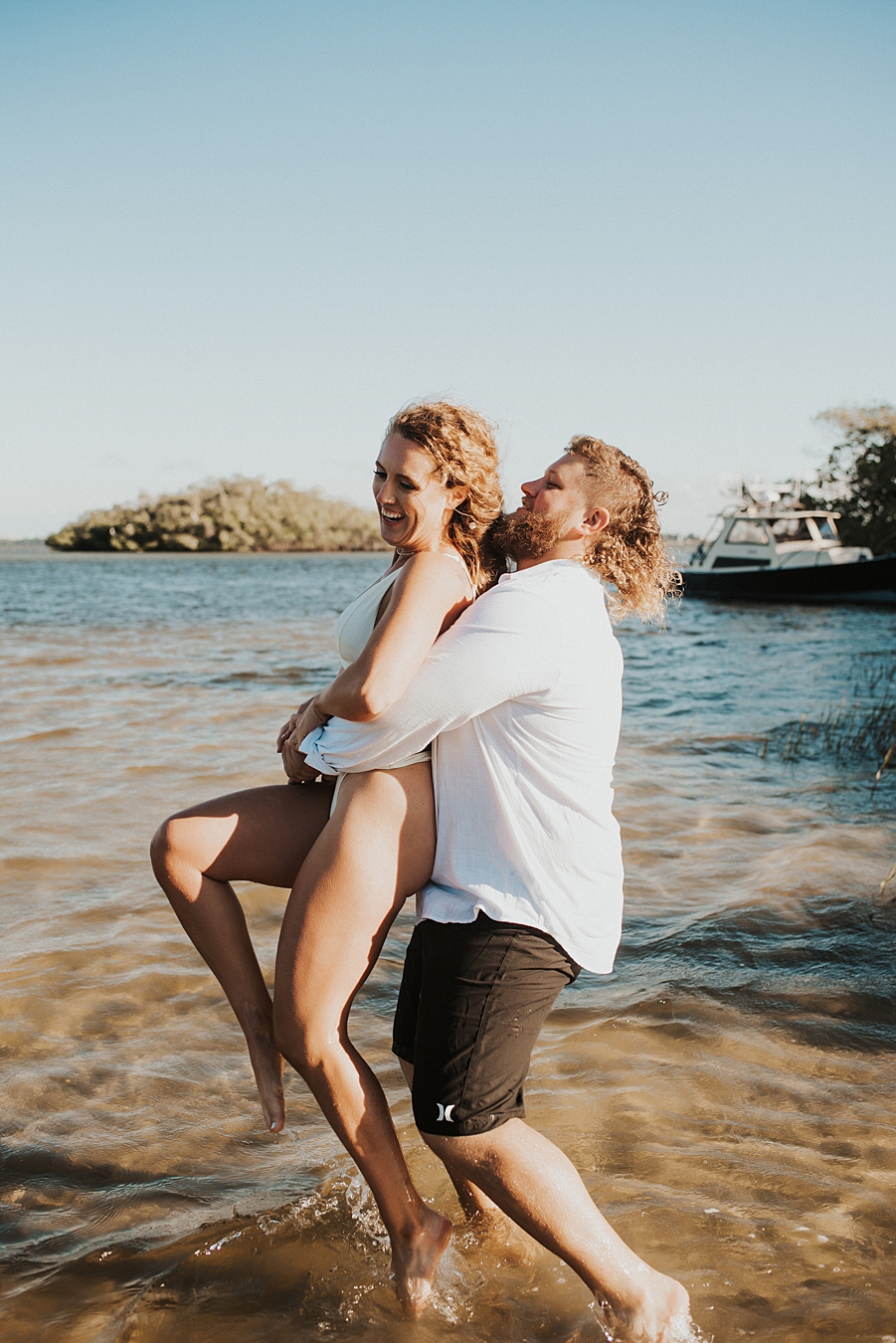 Groom lifting bride into the air in the water