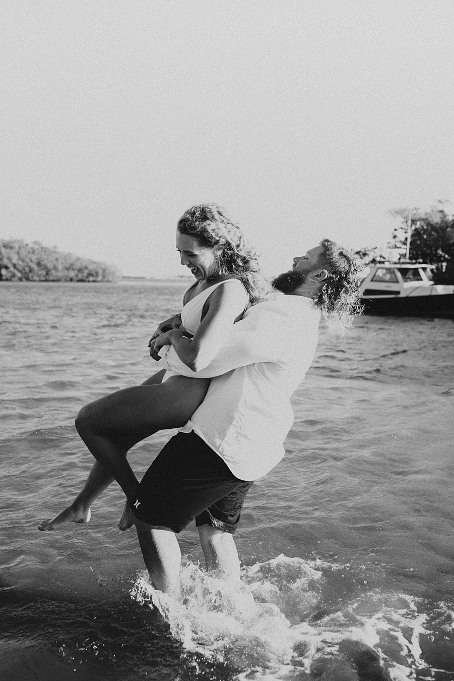 Groom lifting bride into the air in the water