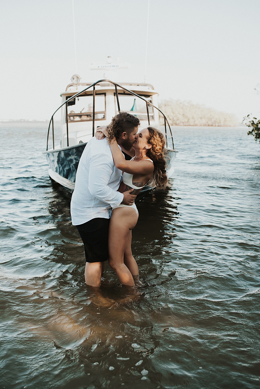 Bride and groom posing in front of fishing boat