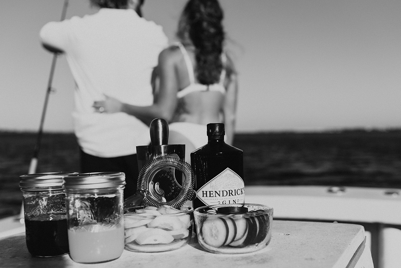 Bride and groom looking out into the ocean with cocktails in front of them