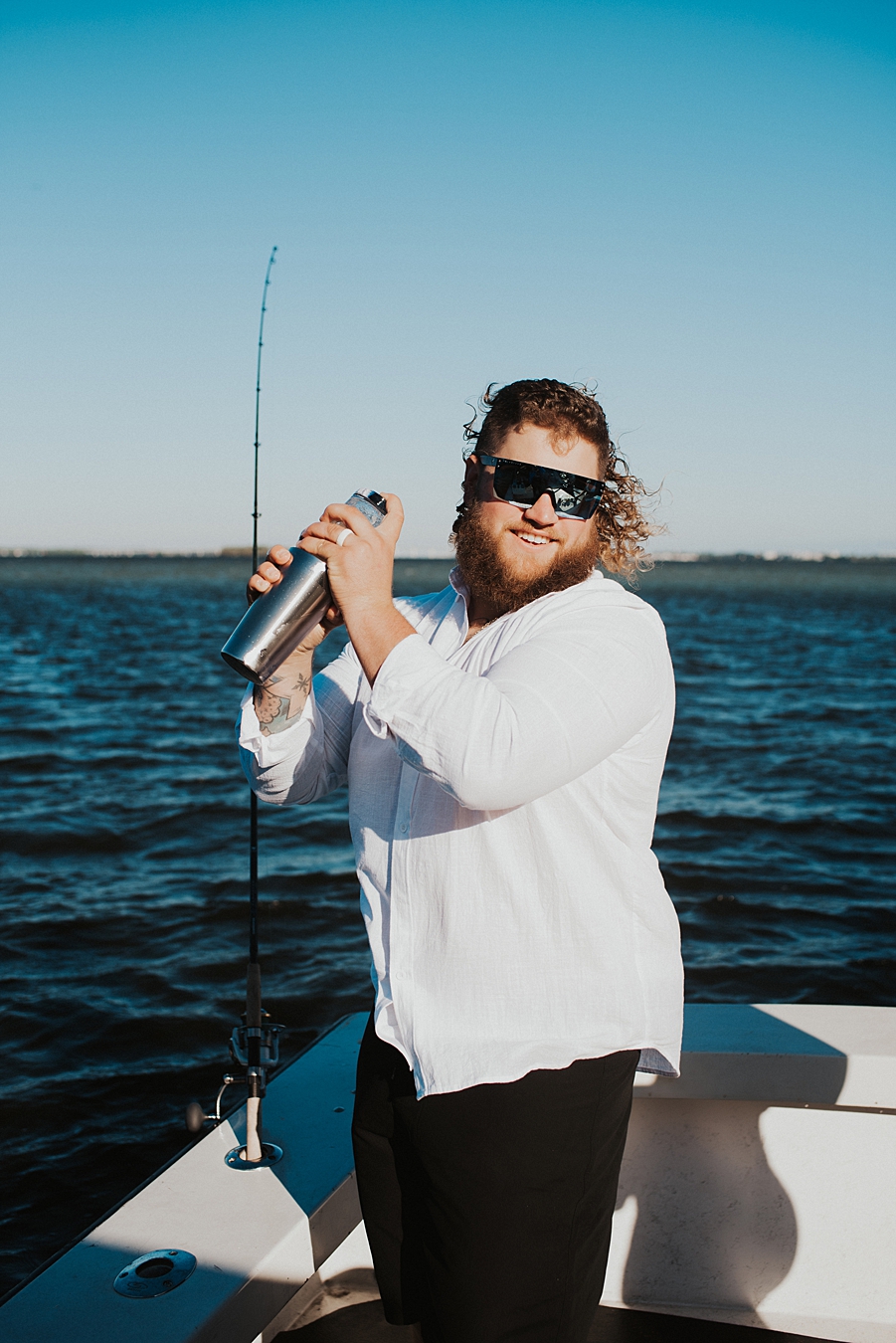 Groom shaking cocktail on back of boat