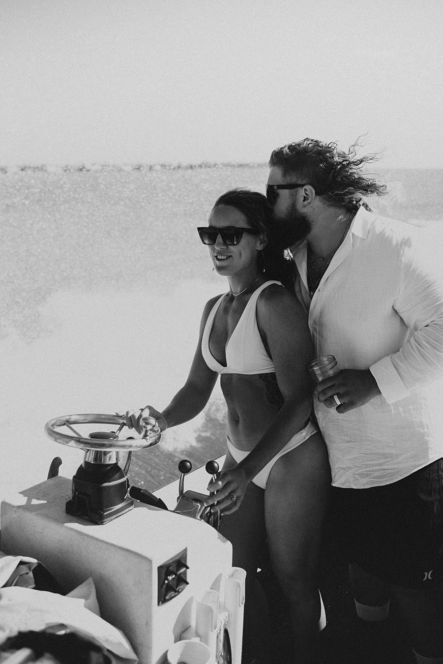 Bride in bikini driving boat during elopement