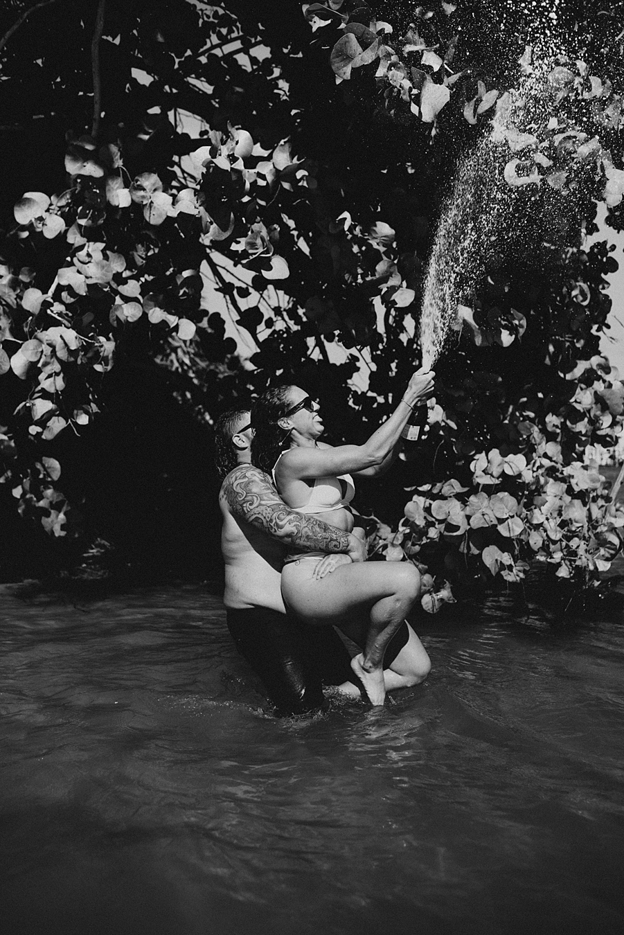 Bride popping champagne in water in front of mangroves