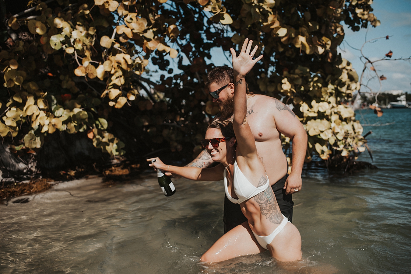 Bride popping champagne in water in front of mangroves