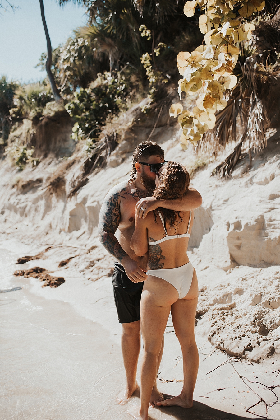 Groom kissing bride in front of sand bar