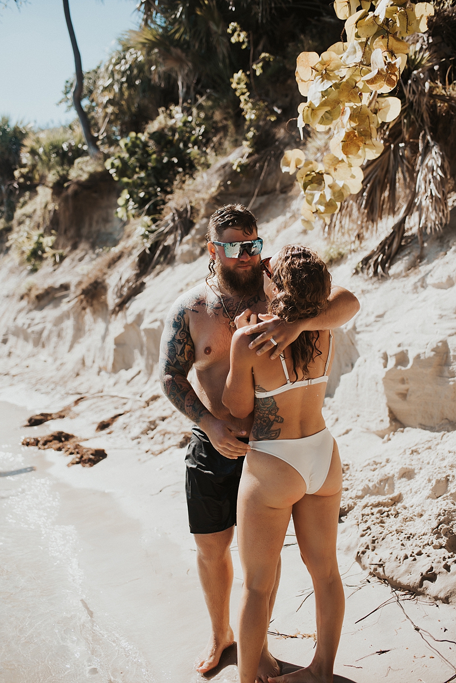 Groom kissing bride in front of sand bar