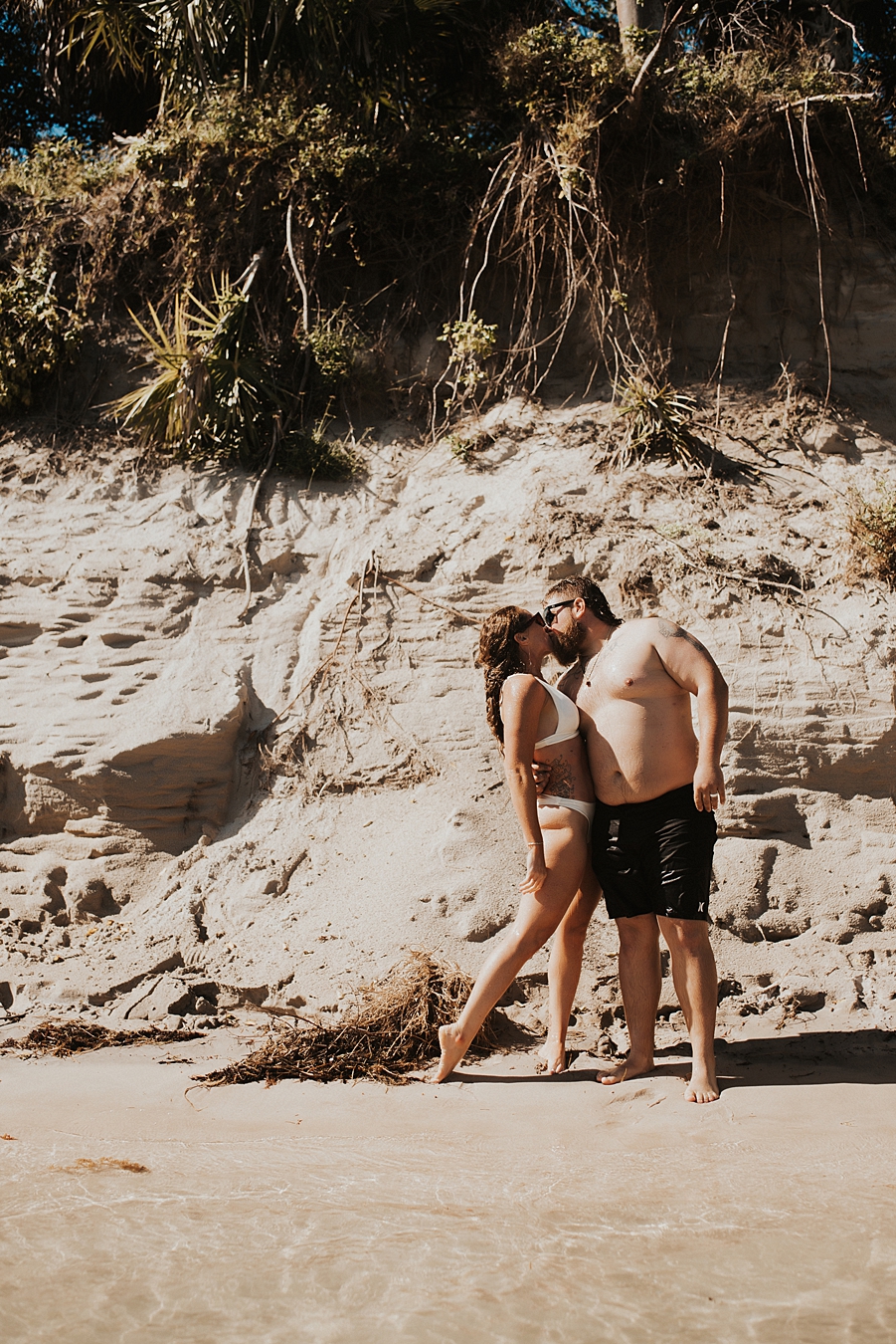 Groom kissing bride in front of sand bar