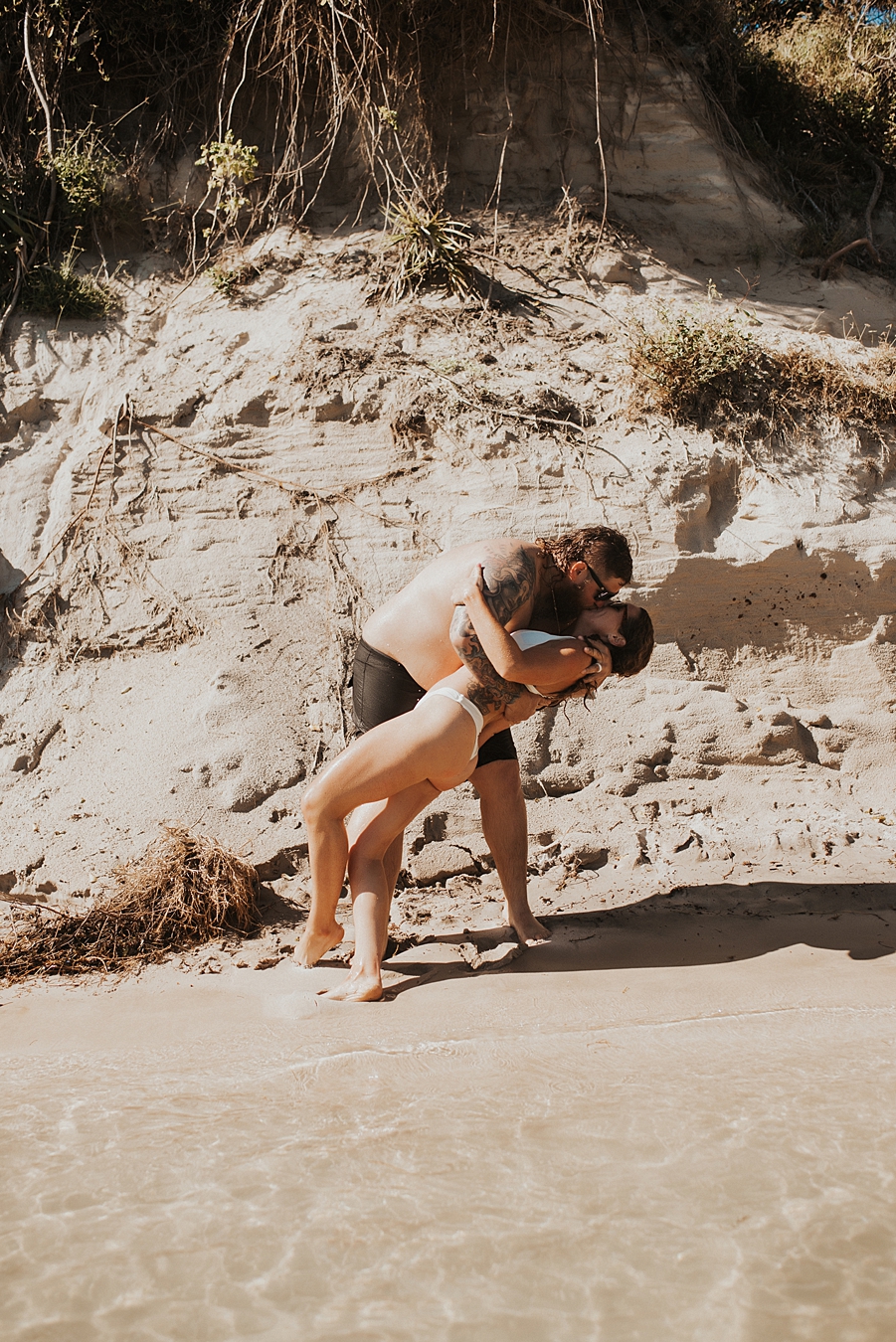 Groom kissing bride in front of sand bar