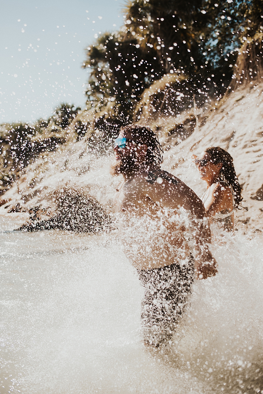 Groom and bride running into water