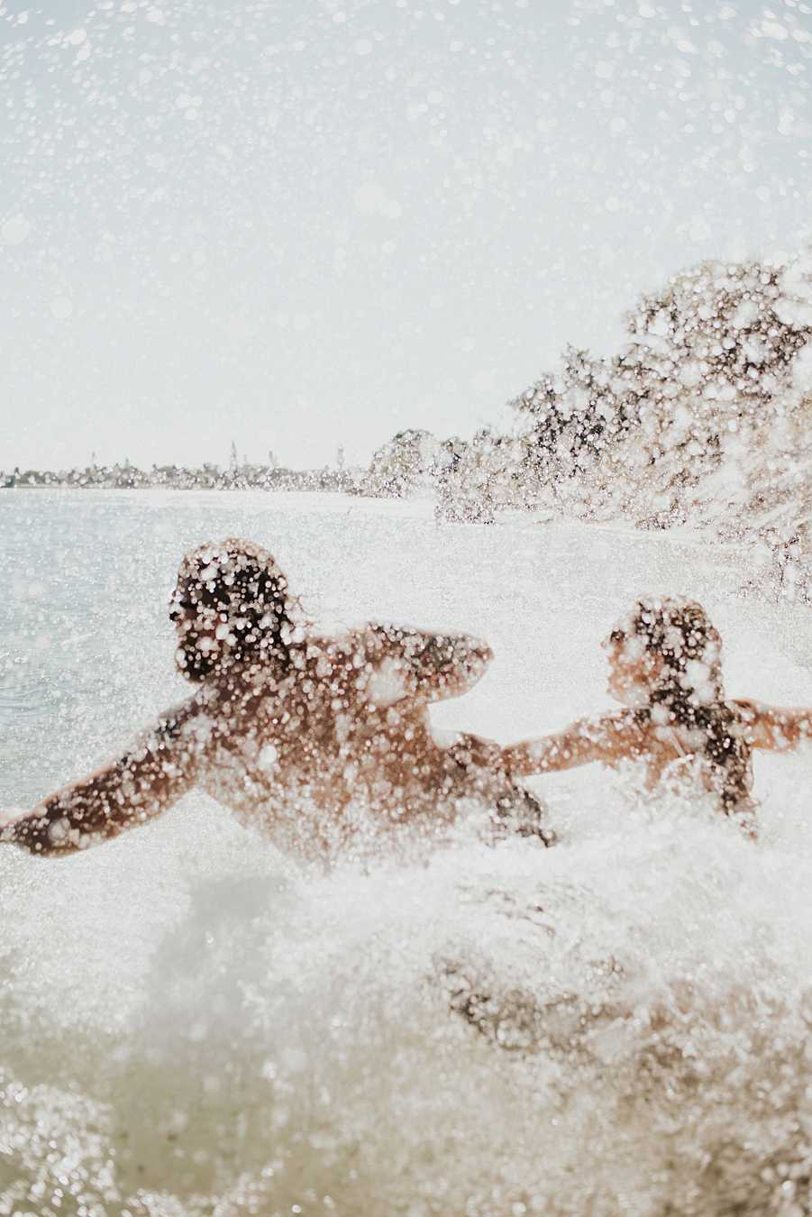 Groom and bride running into water