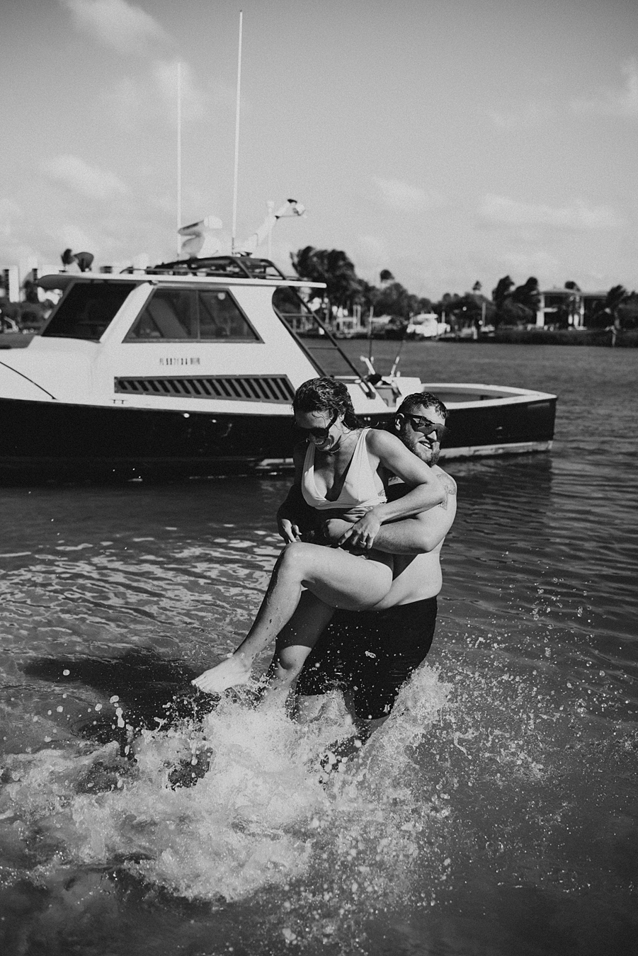 Groom carrying bride into water