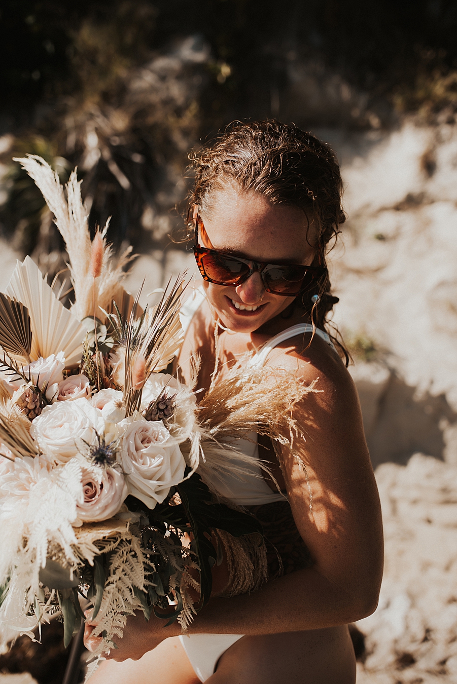 Bride in bikini with dried floral bouquet on front of boat