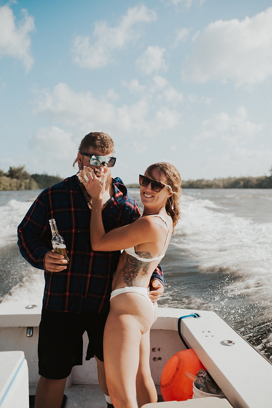 Bride in bikini smashing cake into grooms face on boat