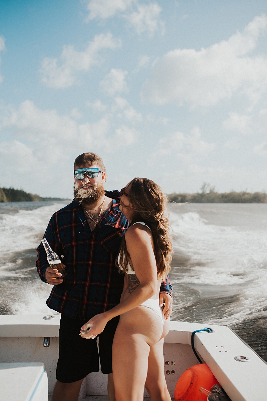 Bride in bikini smashing cake into grooms face on boat