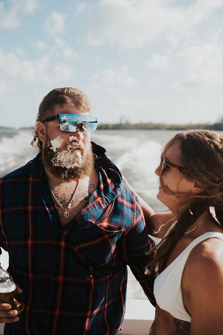 Bride in bikini smashing cake into grooms face on boat