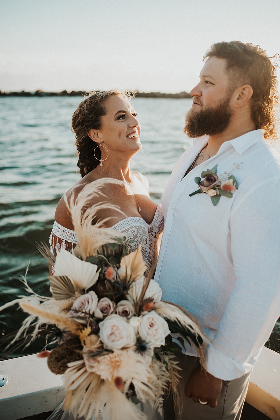 Bride holding bouquet and looking at groom on boat