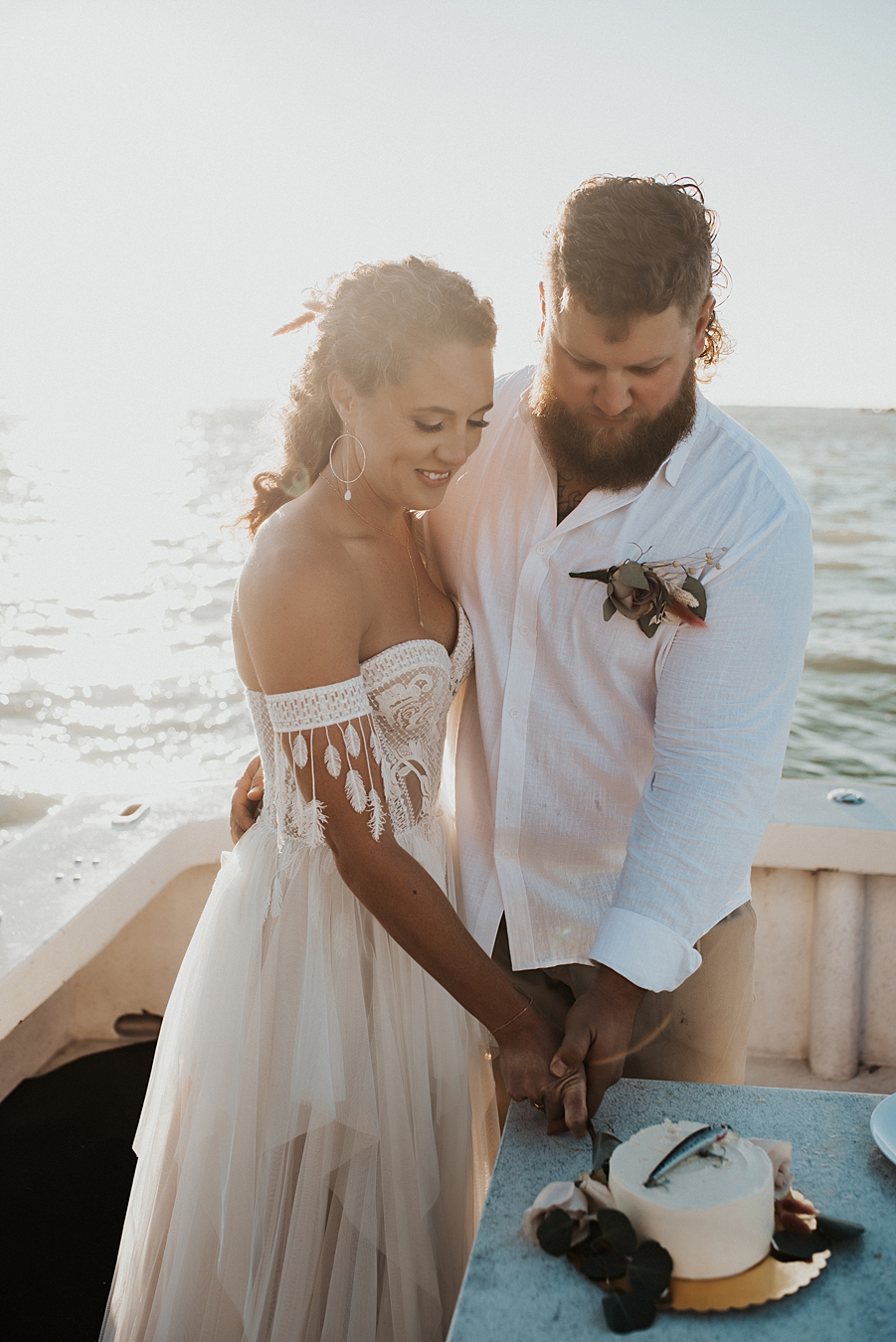 Eloping couple cutting cake on boat
