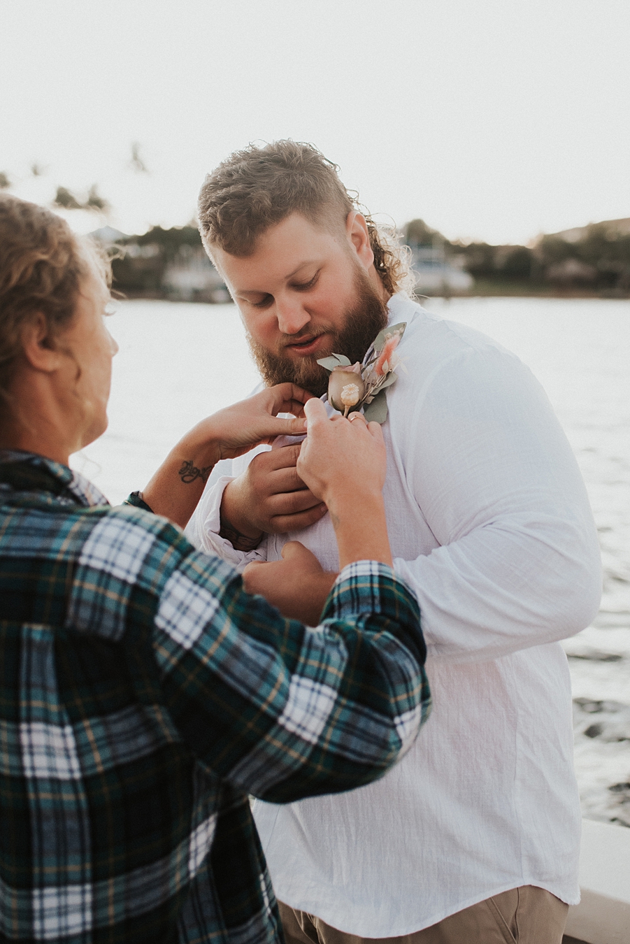 Bride in flannel helping to pin boutonnière on groom