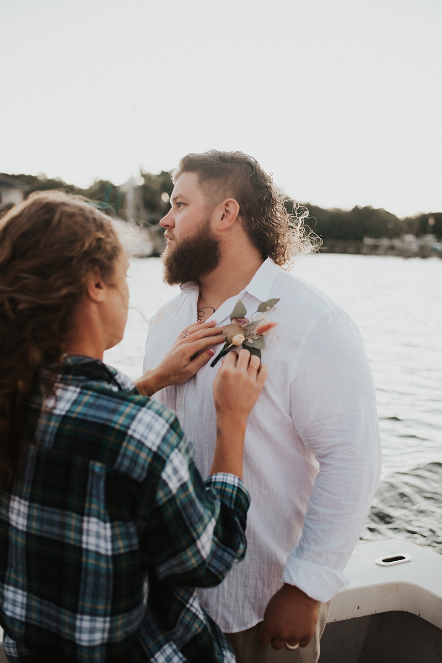 Bride in flannel helping to pin boutonnière on groom