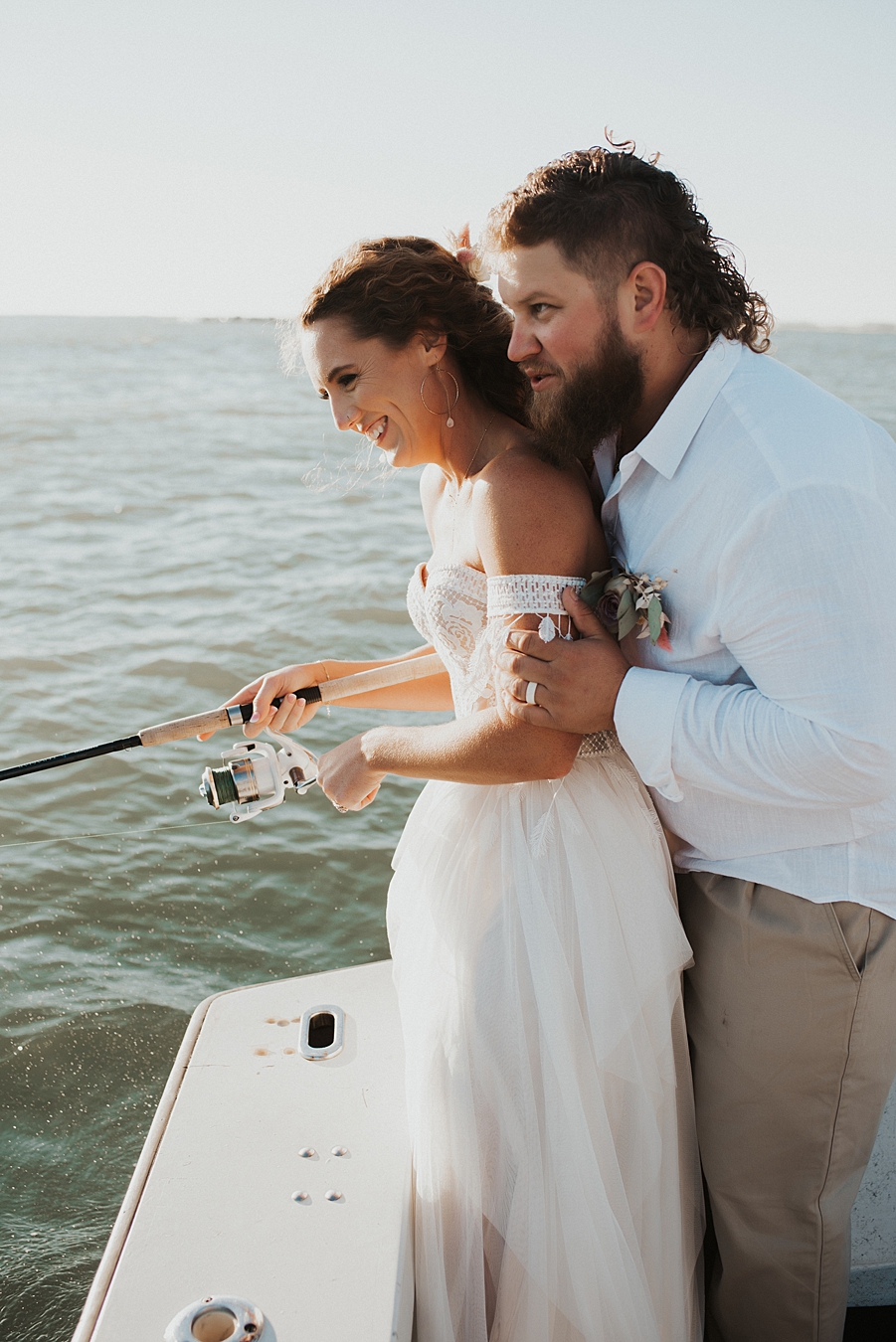 Bride and groom fishing on back of boat