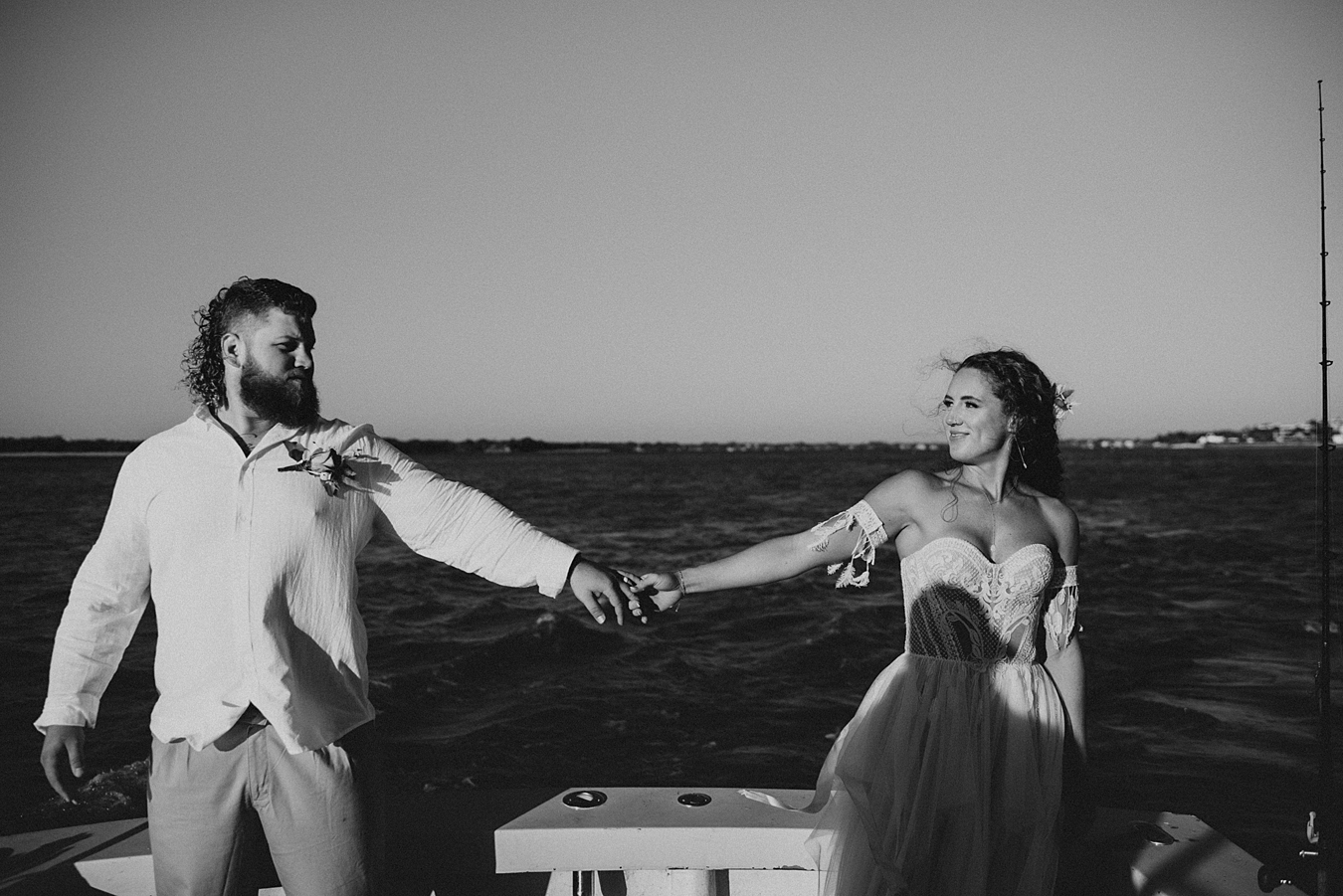 Bride and groom holding one hand on back of baot