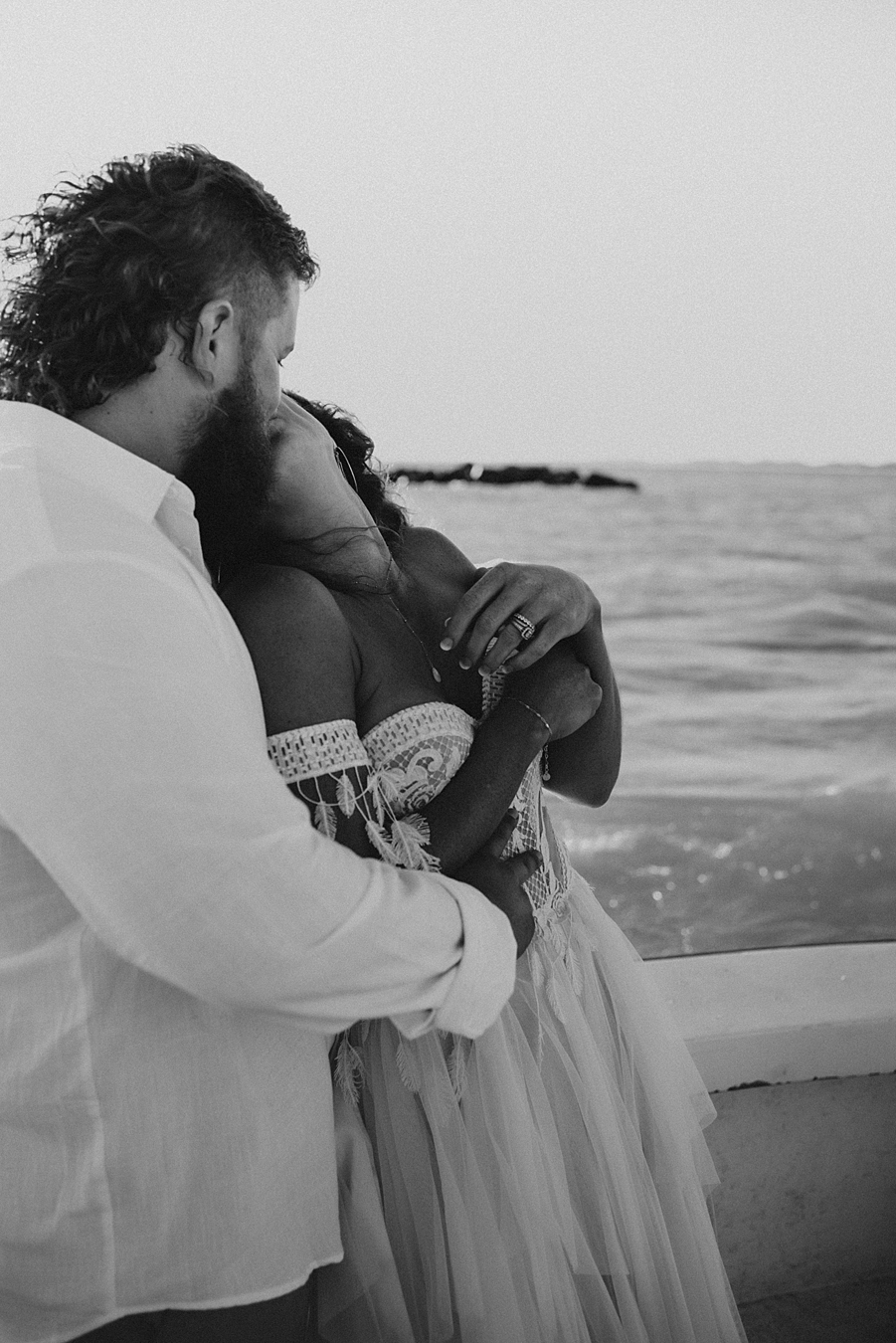 Bride kissing groom on back of boat