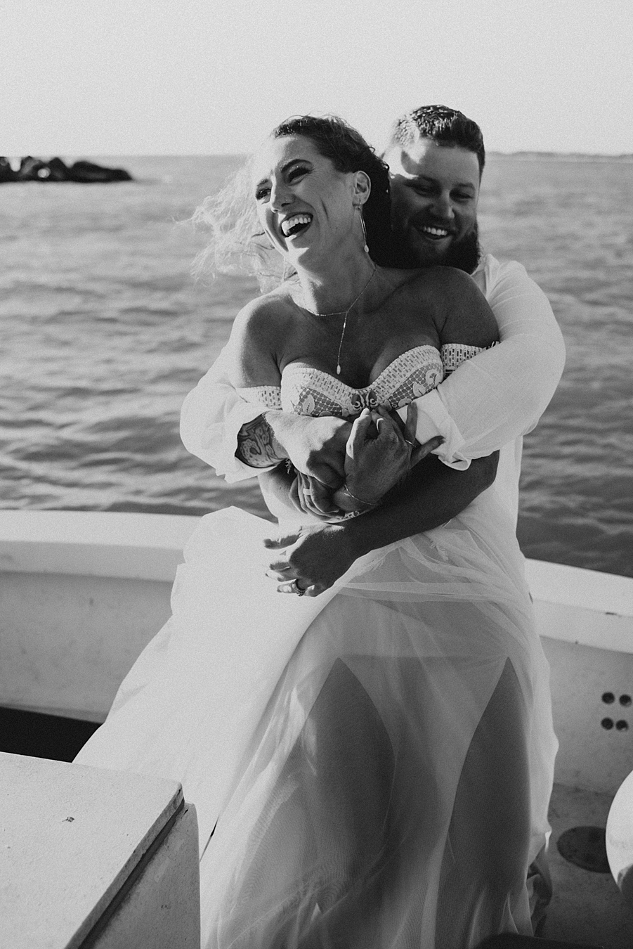 Groom hugging bride from behind on boat