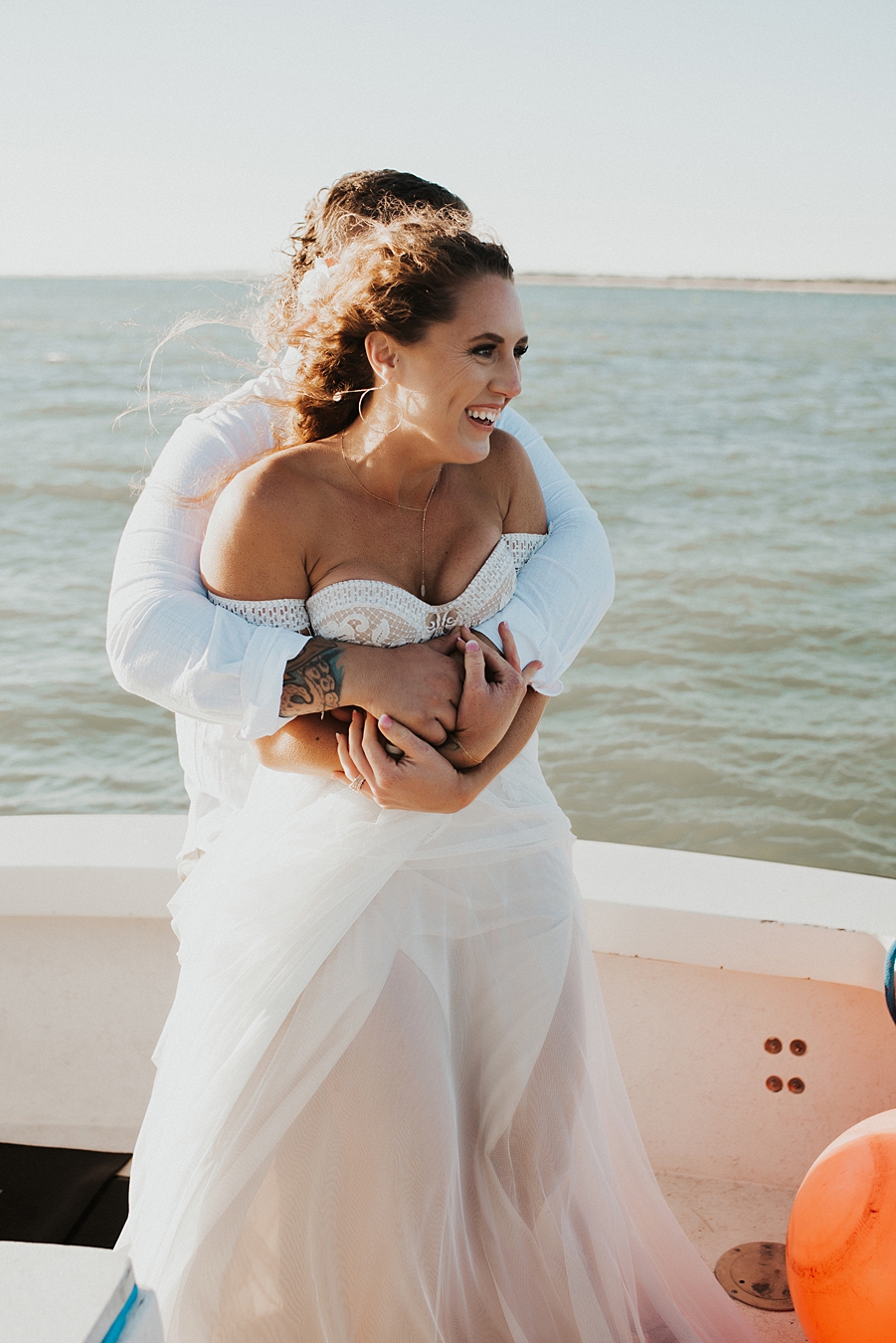 Groom hugging bride from behind on boat