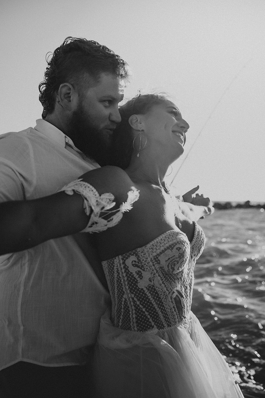 Groom hugging bride from behind on boat