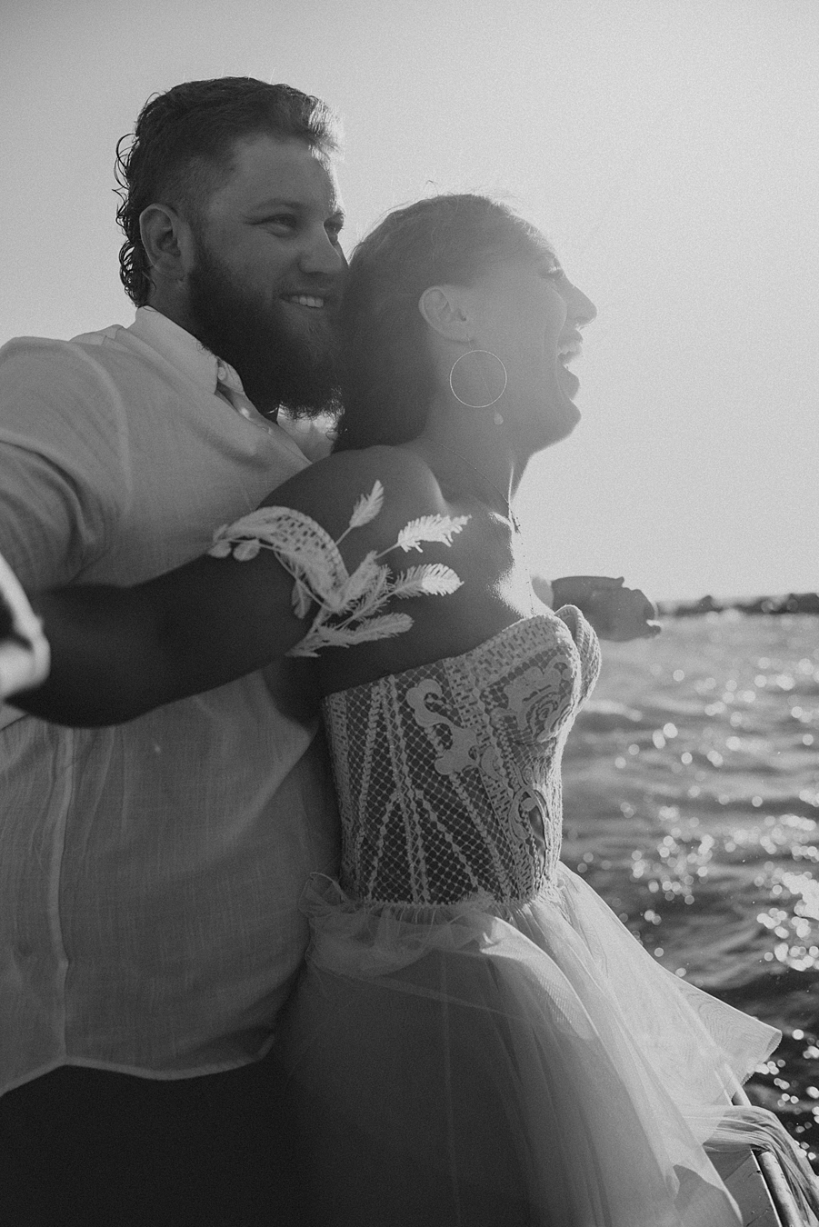 Groom hugging bride from behind on boat