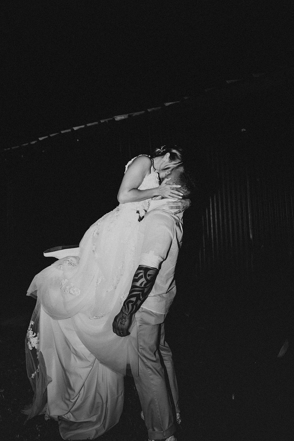 Groom picking up bride and kissing her