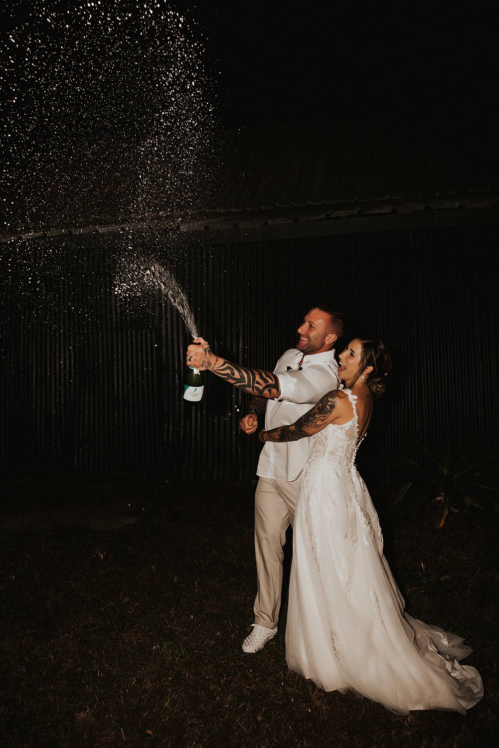 Bride and groom popping champagne at night