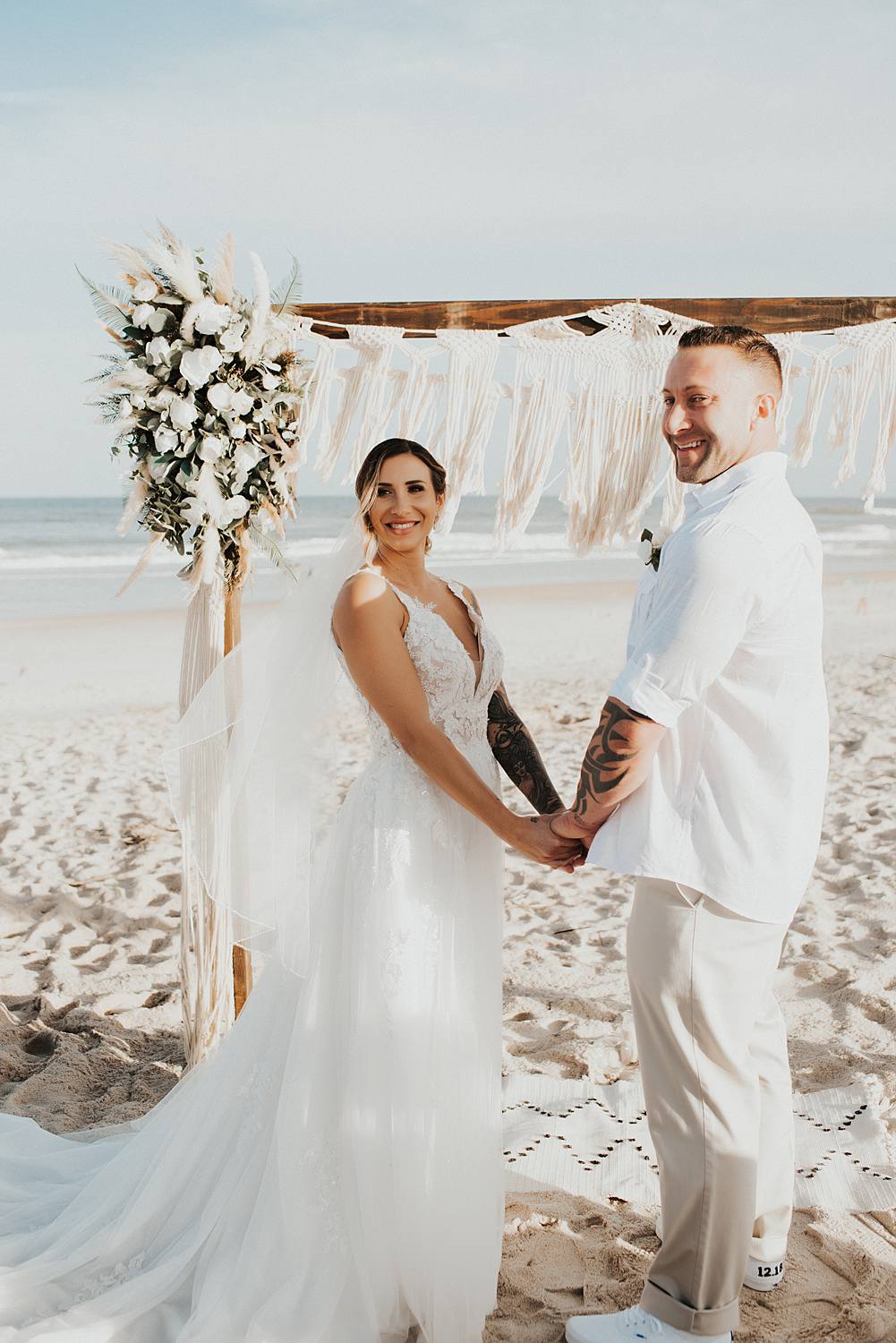 Bride and groom holding hands at beach wedding
