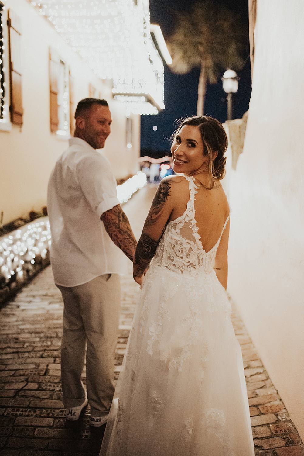 Bride looking back as groom leads her down an alleyway in saint augustine