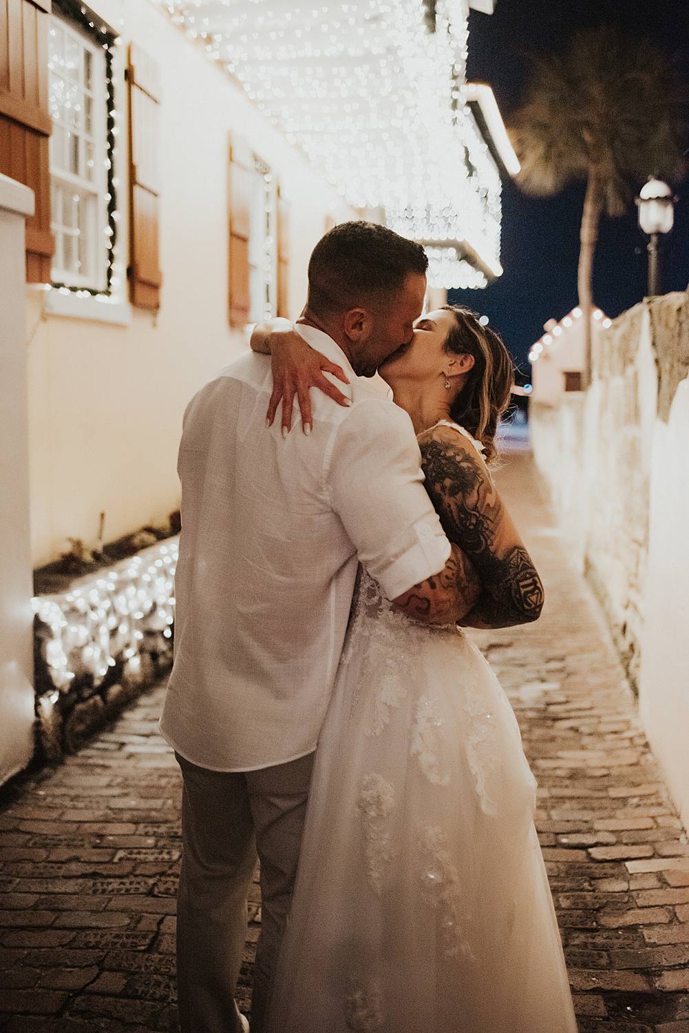 Bride and groom kissing in alleyway during night of lights