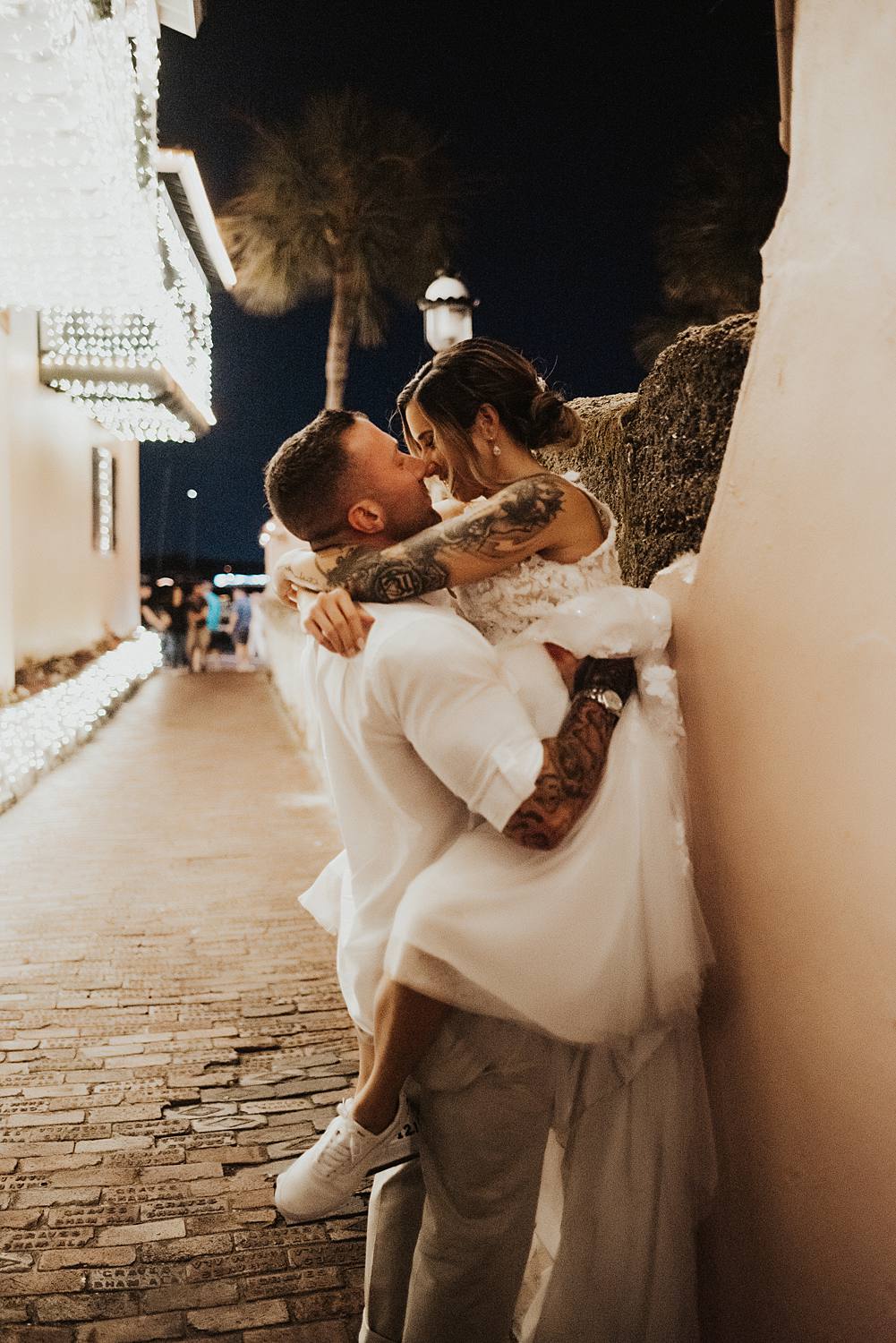 Groom picking up bride and pushing her against a wall in an alleyway