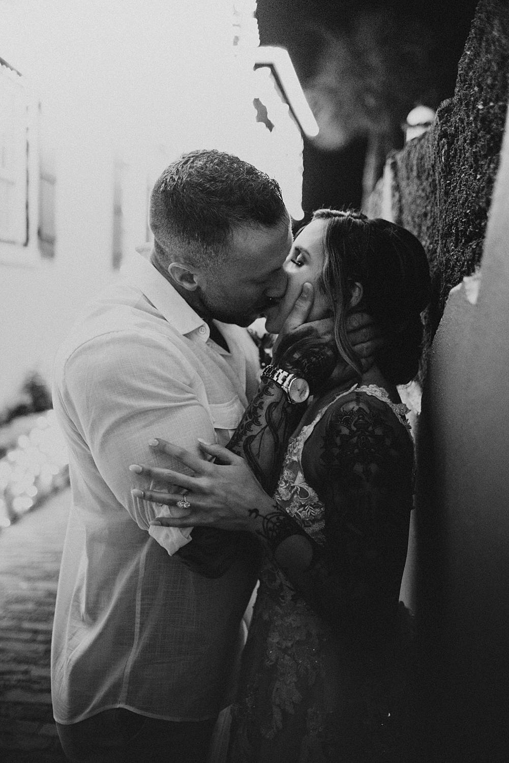 Groom kissing bride against a wall