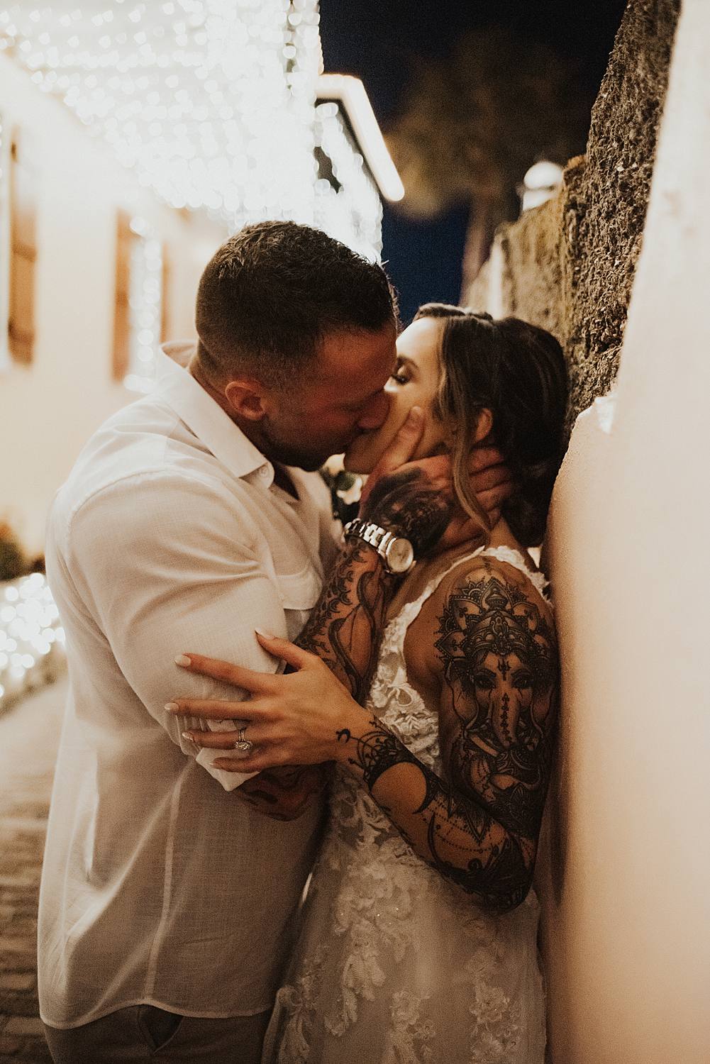 Groom kissing bride against a wall