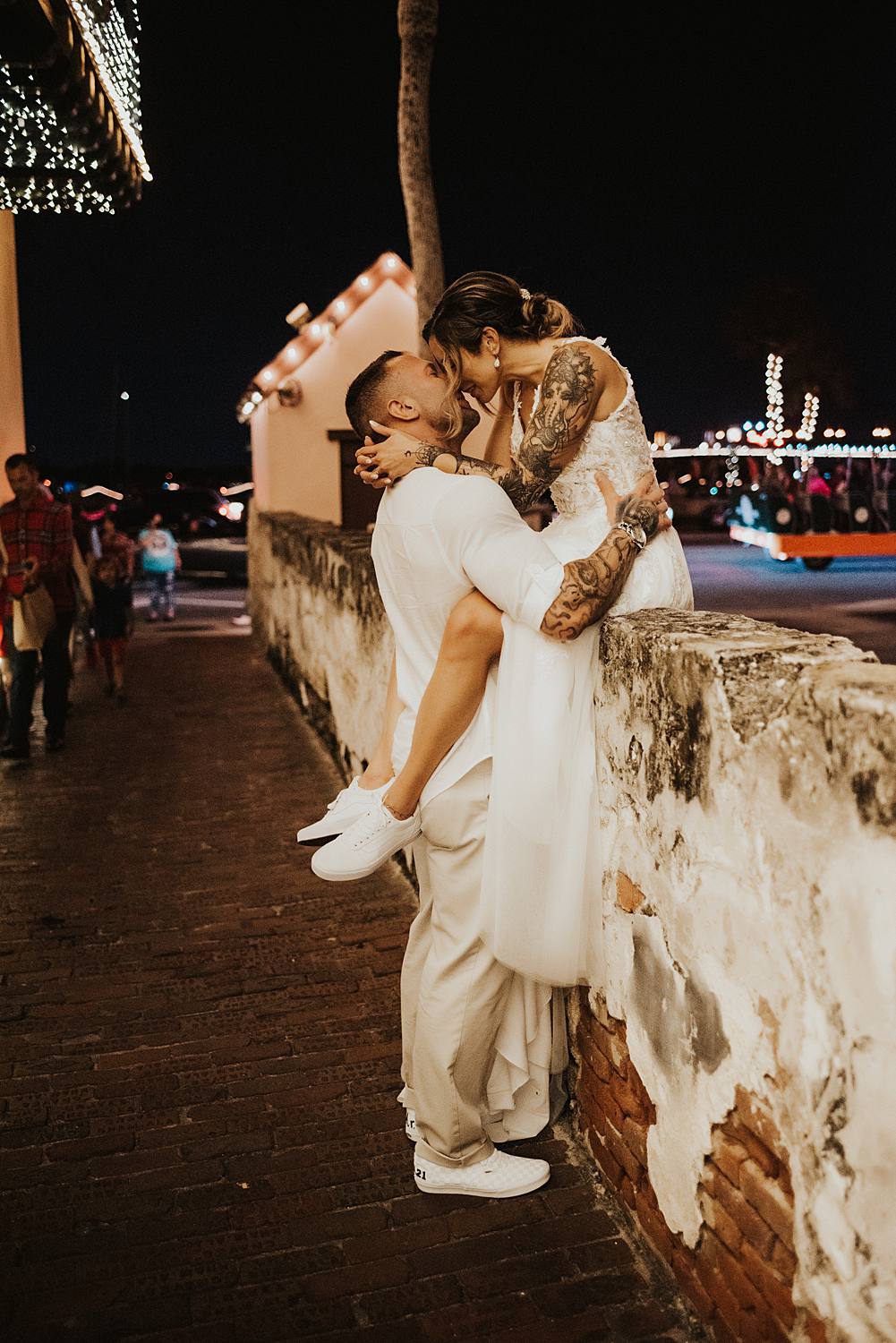 Bride sitting on a ledge kissing groom