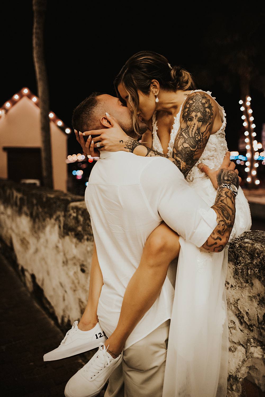 Bride sitting on a ledge kissing groom