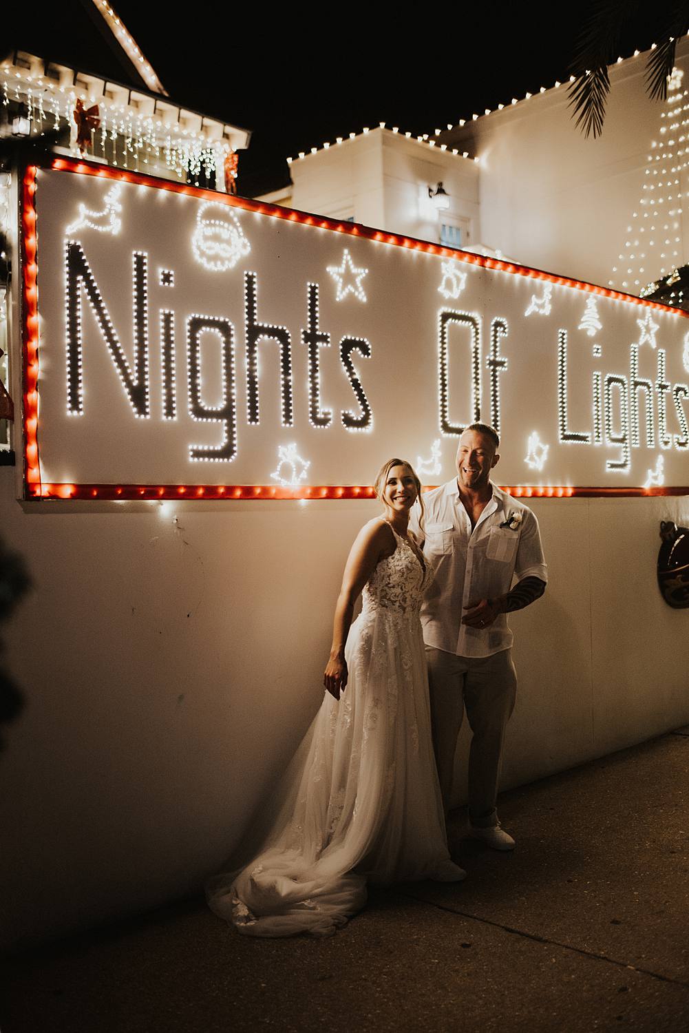 Bride and groom kissing in front of night of lights sign
