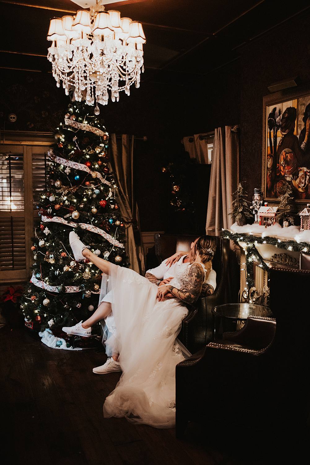 Bride sitting on grooms lap in front of Christmas tree at the Tini Martini