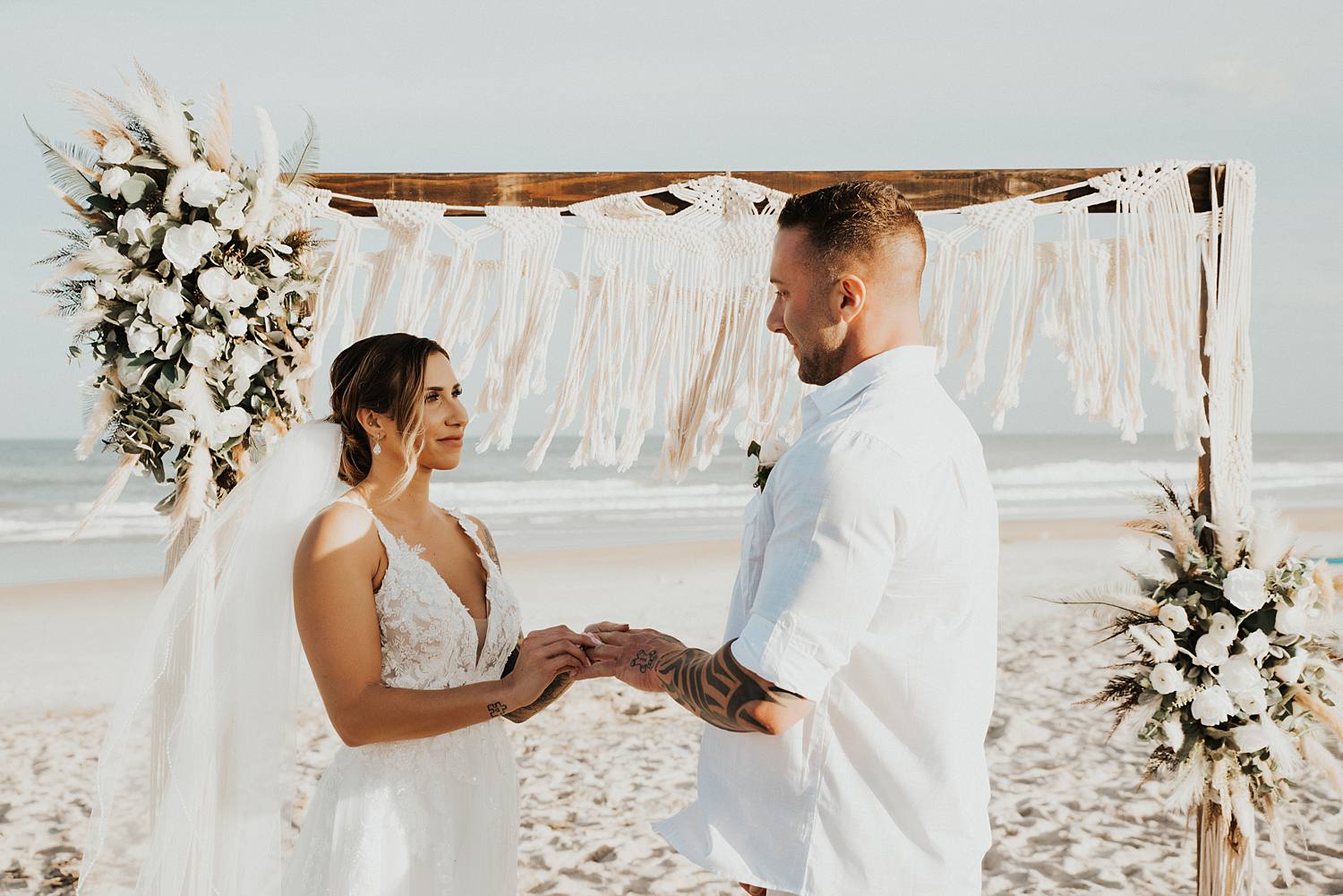 Groom placing ring on brides finger at beach wedding