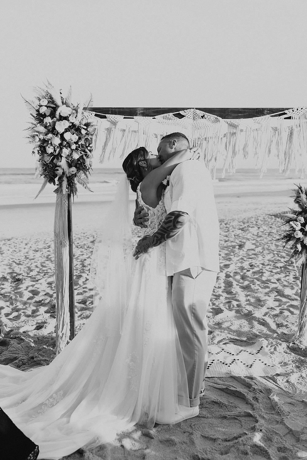 Bride and groom's first kiss at beach wedding