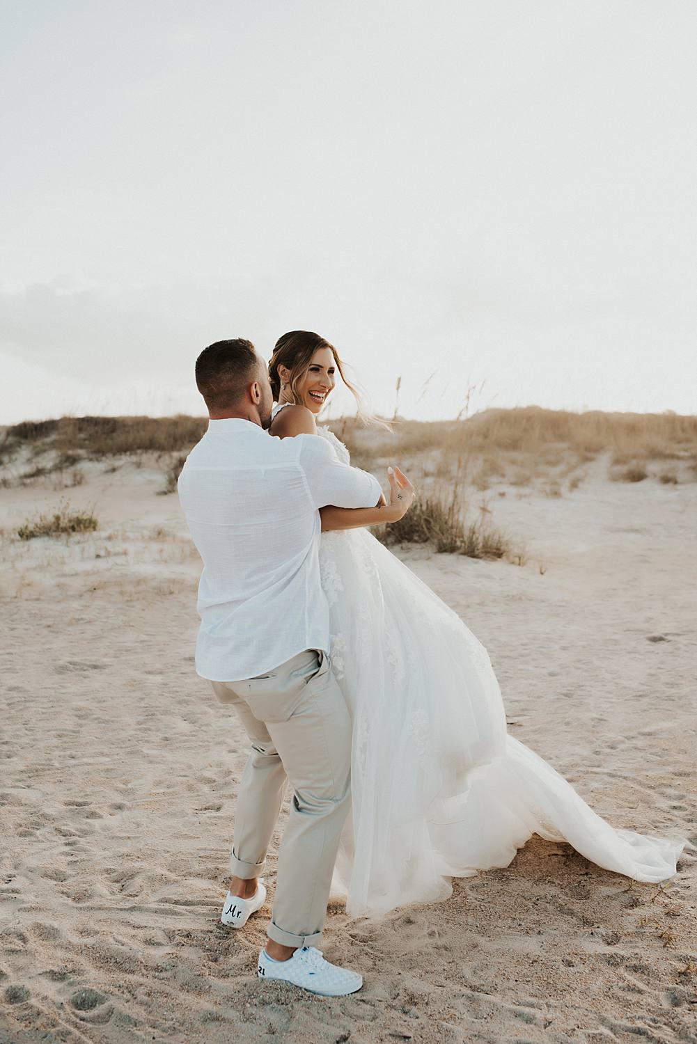 Groom swinging bride on beach
