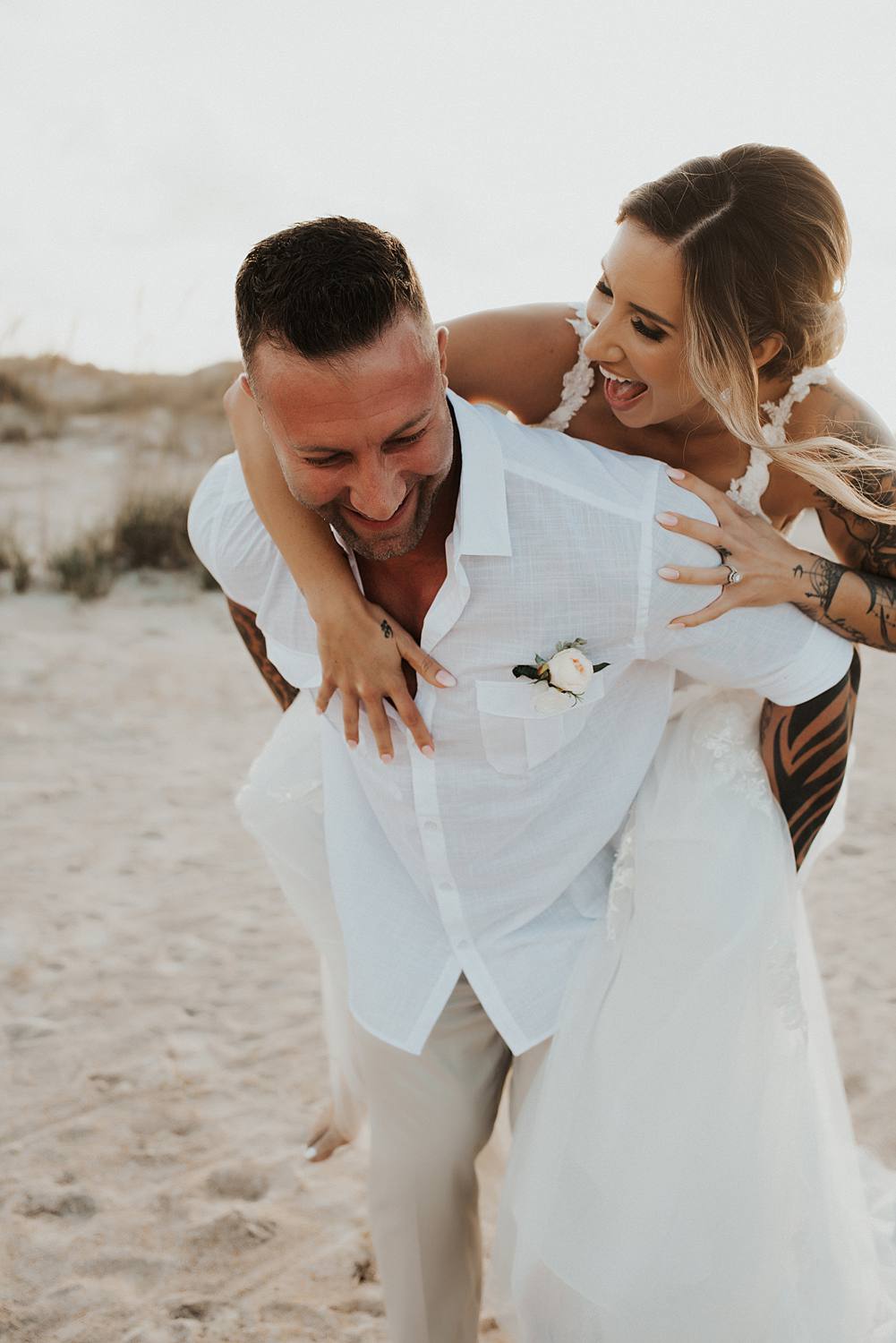 Bride getting piggyback ride from groom on beach