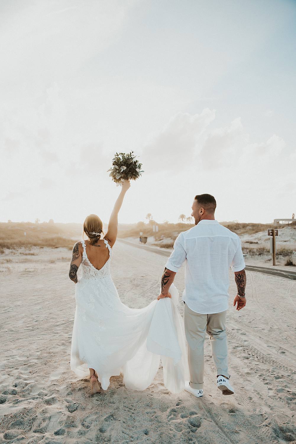 Bride throwing bouquet up into the air Bride and groom walking away on Saint Anastasia beach