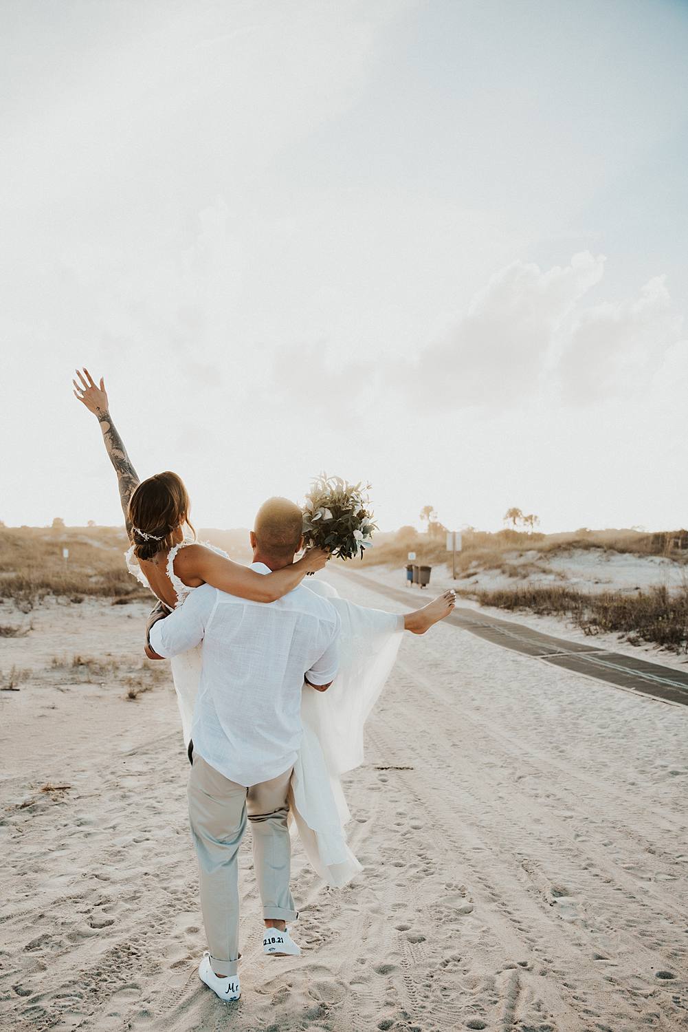Groom carrying bride away on Saint Anastasia beach