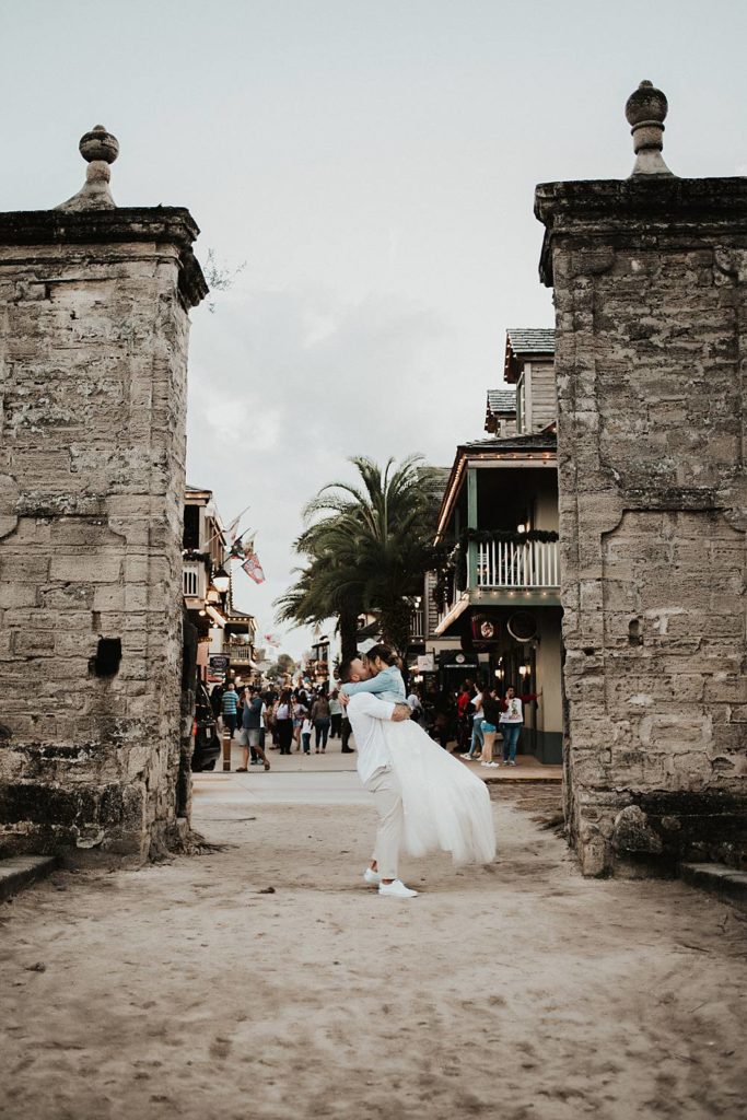 Groom swinging bride in jean jacket on Saint George street