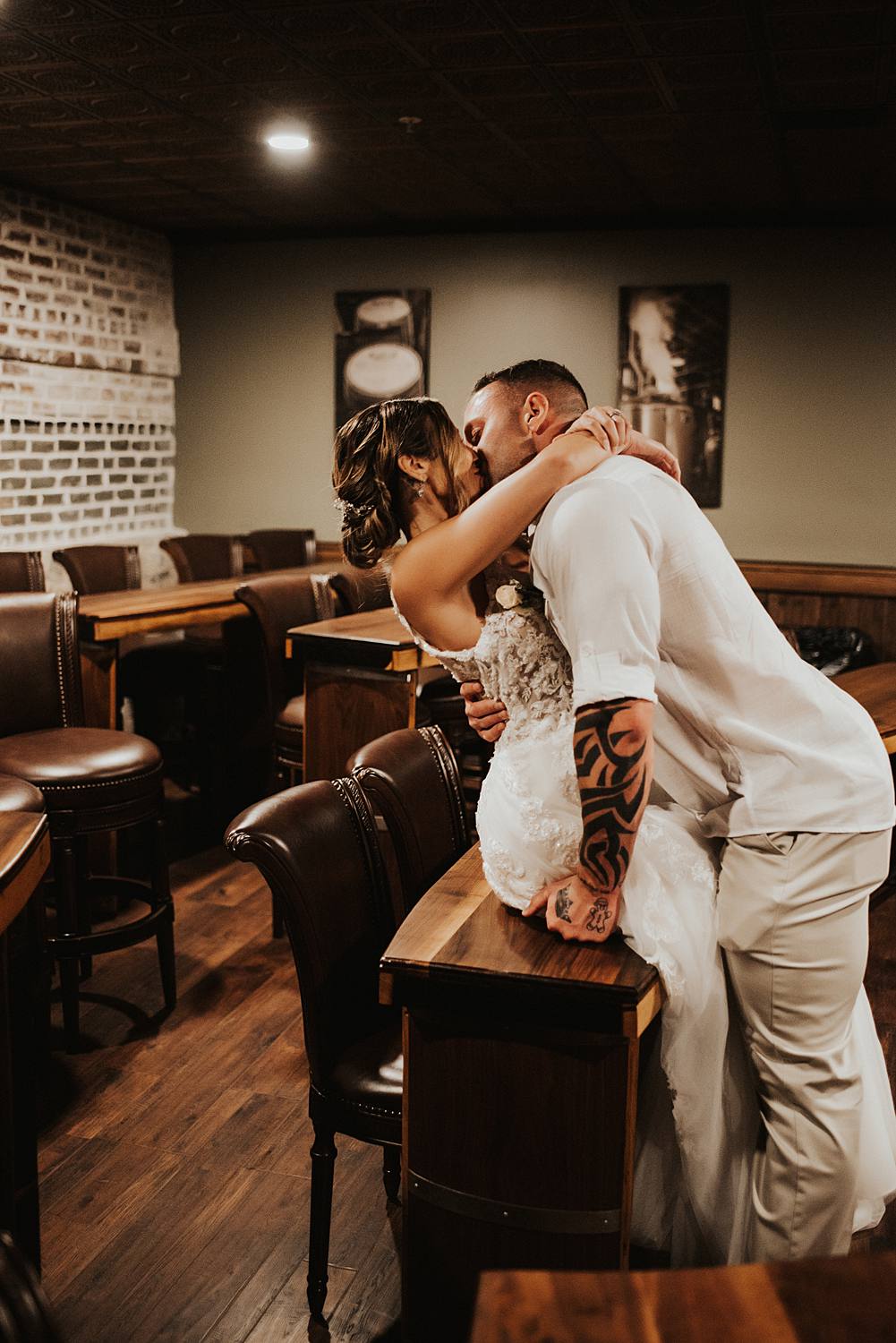 Bride and groom kissing on desk at Saint Augustine Distillery